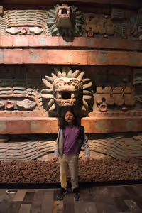 Tejas pretends to be a Quetzalcoatl, in front of a reproduction of the Quetzalcoatl temple pyramid façade that we had seen the previous day in Teotihuacán